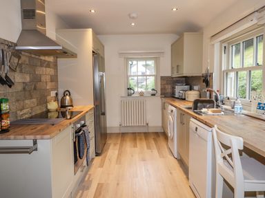A kitchen with wooden countertops white cabinets stainless steel appliances and a window at Highfold in Ambleside