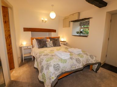 A bedroom with a double bed and patterned bedding with nightstands and lamps at Highfold in Ambleside