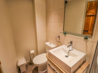 A small bathroom with a toilet sink mirror and trash bin at Highfold in Ambleside