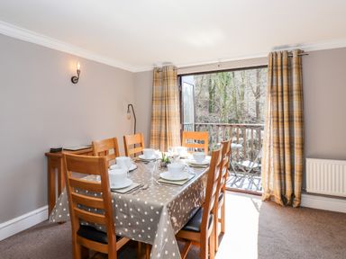 A dining room with a table set for six near a balcony with outdoor furniture at Ghyll View in Ambleside