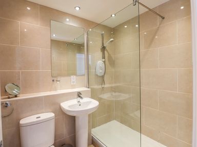 A bathroom with a toilet sink mirror and a glass shower enclosure at Ghyll View in Ambleside