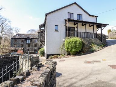 An outdoor view of two houses with stone walls and a driveway at Ghyll View in Ambleside