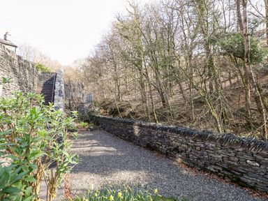A stone terrace with stairs and a gravel surface overlooking trees at Ghyll View in Ambleside