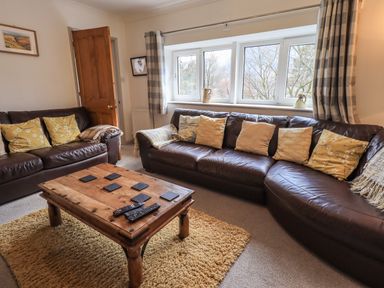 A living room with brown leather sofas and a wooden coffee table at Rawfell in Great Langdale