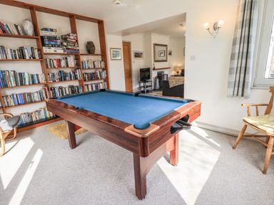 A room with a pool table a bookshelf filled with books and board games and chairs at Rawfell in Great Langdale