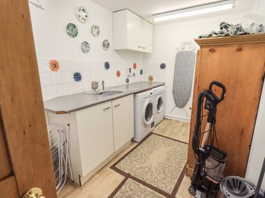 A utility room with a sink washing machine ironing board and vacuum cleaner at Rawfell in Great Langdale