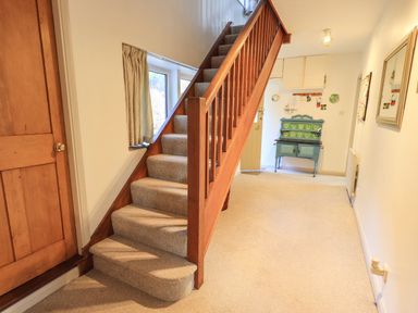 An entryway with carpeted stairs wooden door green cabinet and beige walls at Rawfell in Great Langdale