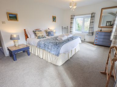 A bedroom with a bed bedside tables a dresser a mirror window and carpet at Rawfell in Great Langdale