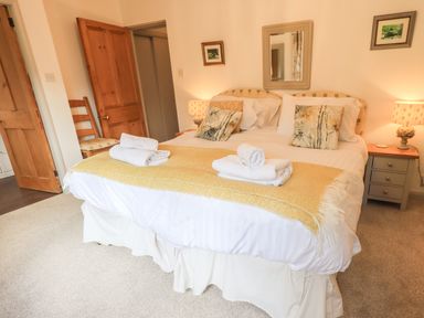 A bedroom with a double bed two bedside tables with lamps a chair and wooden doors at Rawfell in Great Langdale
