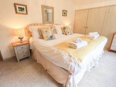 A bedroom with a double bed pillows and folded towels on the bed beside bedside tables with lamps at Rawfell in Great Langdale