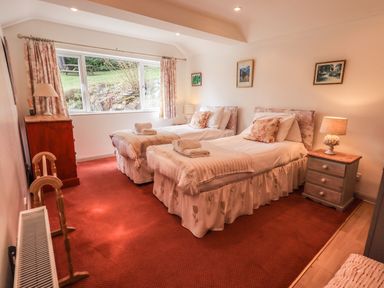 A bedroom with two single beds bedside tables lamps and a chest of drawers at Rawfell in Great Langdale