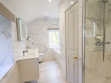 A bathroom with a double sink vanity mirror toilet bathtub door and shower at Rawfell in Great Langdale