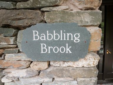 A stone plaque with the words Babbling Brook mounted on a stone wall at Babbling Brook in Ambleside
