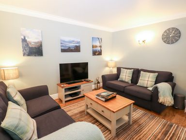 A living room with two sofas a coffee table a television and landscape pictures on the wall at Babbling Brook Ambleside