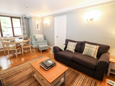 A living room with a sofa, armchair, coffee table, dining table and chairs at Babbling Brook in Ambleside