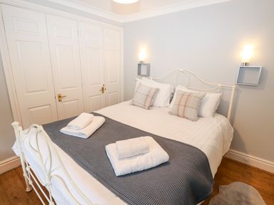 A bedroom with a white metal bed frame with pillows and folded towels at Babbling Brook in Ambleside
