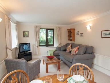 A living room with a gray sofa and armchair a wooden coffee table and a television at Over Ghyll in Ambleside