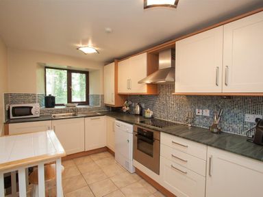 A kitchen with white cabinets a green countertop tiled floor and a window at Over Ghyll in Ambleside