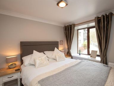 A bedroom with a double bed bedside tables and a window with curtains at Over Ghyll in Ambleside