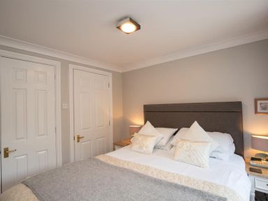 A bedroom with a double bed pillows bedside tables lamps and two closed white doors at Over Ghyll in Ambleside