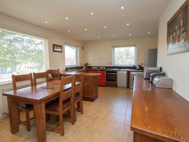 A kitchen with wooden dining table and chairs red stove and appliances at Bield How in Ambleside