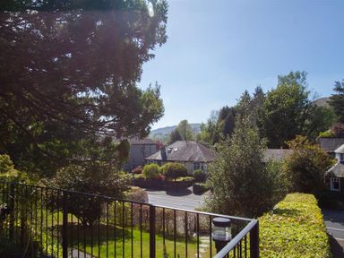 A view of a residential neighborhood with trees and houses from a balcony at Bield How in Ambleside