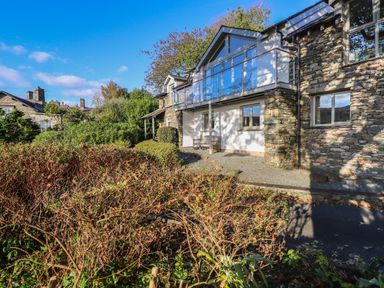 A stone house with a balcony and bushes in front at Garden House Ambleside