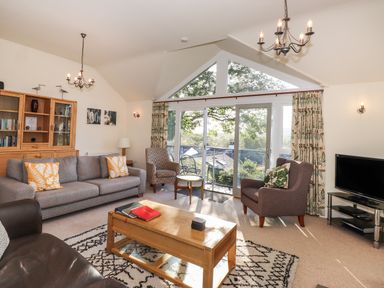 A living room with sofas armchairs a coffee table and a television at Garden House in Ambleside