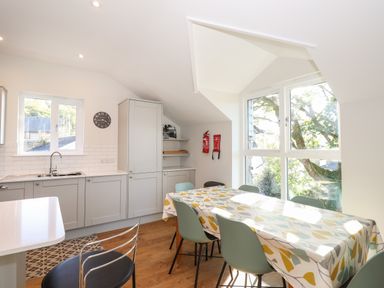A kitchen with a dining table and chairs next to large windows at Garden House in Ambleside