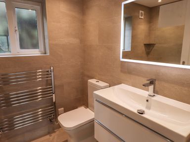 A bathroom with a toilet sink vanity with faucet mirror and heated towel rail at Garden House in Ambleside