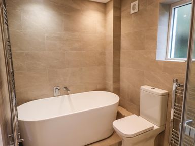 A bathroom with a bathtub toilet window and towel radiator at Garden House in Ambleside
