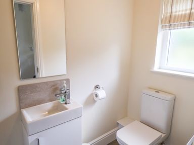 A bathroom with a sink cabinet mirror toilet and window with striped blind at Garden House in Ambleside