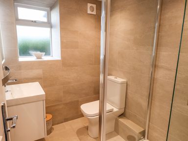 A small bathroom with a toilet sink window and shower at Garden House in Ambleside