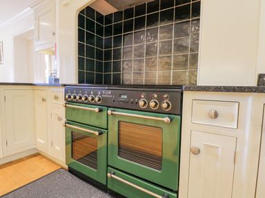 A kitchen with a green double oven and black tiled backsplash at Orchard House in Ambleside