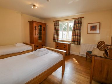 A bedroom with two single beds wooden furniture and a window with patterned curtains at Orchard House in Ambleside