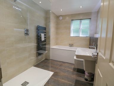 A bathroom with a walk in shower bathtub sink toilet and window at Orchard House in Ambleside