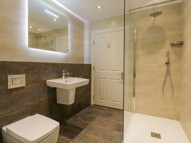 A bathroom with a toilet sink mirror and walk in shower at Orchard House in Ambleside