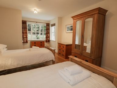 A bedroom with two single beds wooden wardrobe and chest of drawers at Orchard House in Ambleside