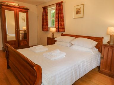 A bedroom with a wooden bed and two nightstands with lamps at Orchard House in Ambleside