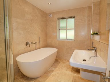 A bathroom with a freestanding bathtub a sink and a window at Orchard House in Ambleside
