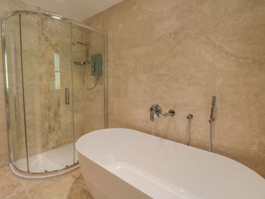 A bathroom with a freestanding bathtub and a glass shower enclosure at Orchard House in Ambleside