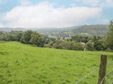A green grassy field with trees and a town in the background at Orchard House in Ambleside