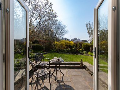 A garden patio with two metal chairs and a small table set with a teapot and cups at Bank Foot Ambleside