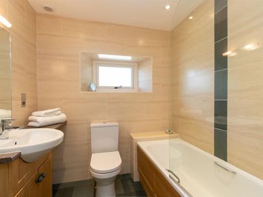 A bathroom with a sink cabinet toilet bathtub and window at Bank Foot in Ambleside