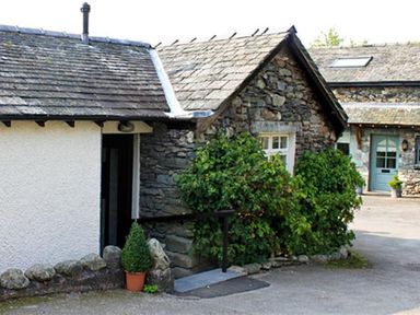 An exterior view of stone cottages with shrubs and a potted plant at Bank Foot in Ambleside