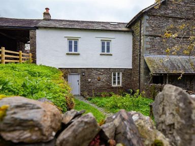 A stone and white two-story cottage with a small garden and wooden fence at Janes Cottage in Hawkshead