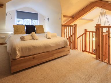 A bedroom with a bed folded towels pillows wooden railing and slanted ceiling at Janes Cottage in Hawkshead