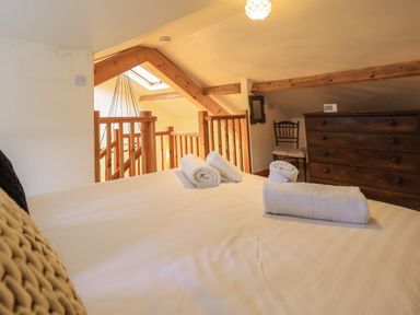 A bedroom with a bed with rolled towels a wooden chest of drawers and a wooden chair at Janes Cottage in Hawkshead