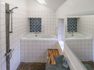 A bathroom with a bathtub shower and a large mirror at Janes Cottage in Hawkshead