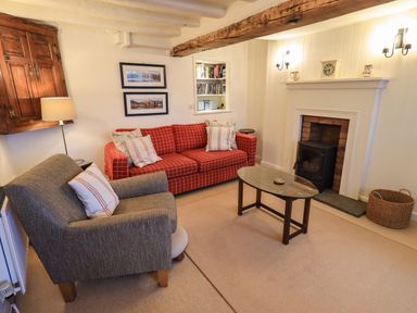A living room with a fireplace two sofas a wooden coffee table and framed pictures at Nurses Cottage in Hawkshead